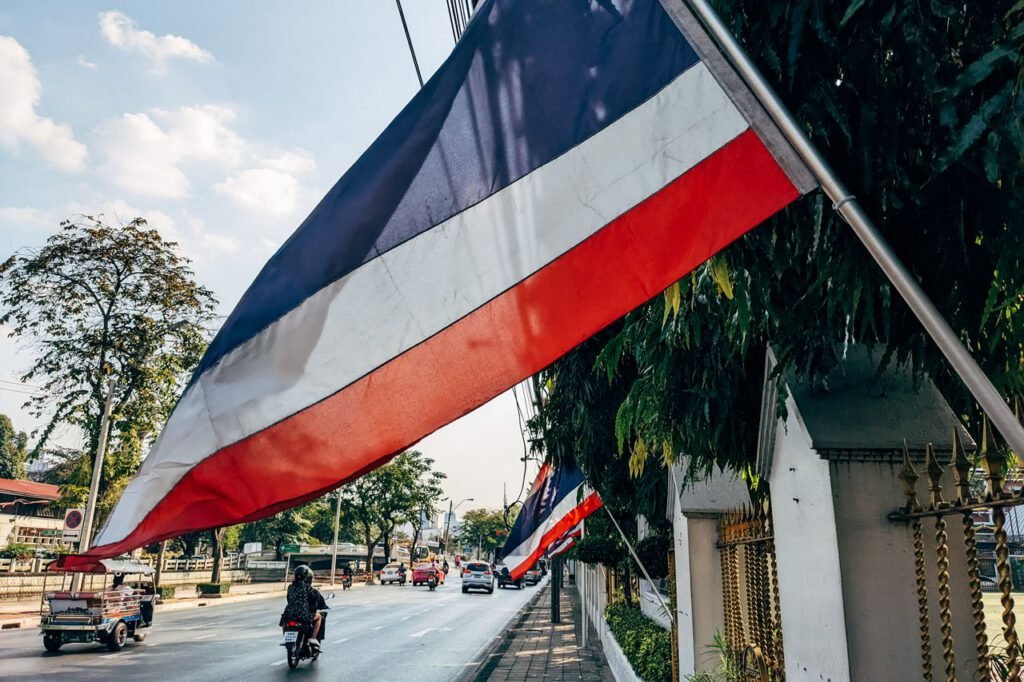 Street scene in Thailand with flags lining the road, showcasing local culture.